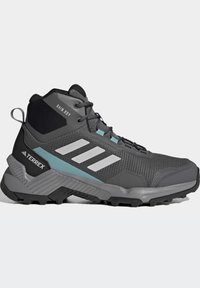 Stivali da trekking grigi con design a metà altezza. Materiale in mesh e sintetico, con accenti azzurri chiari e suola in gomma testurizzata con scanalature.
