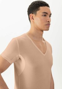 Korte mouwen V-hals shirt in tan, gemaakt van textuurstof, met een aansluitend ontwerp en naadloze okselafwerking.