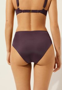 Hoch geschnittene Bikiniunterteile in tiefem Lila, aus glattem Stoff, nahtlosem Design und minimaler Hardware, mit einem klassischen Schnitt und moderater Abdeckung.