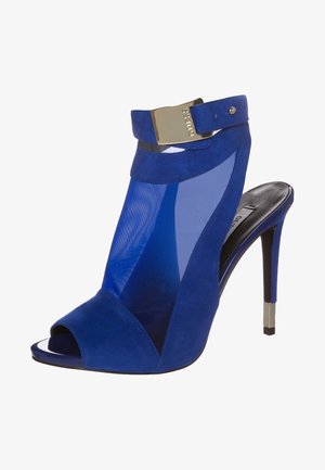 Sandale à talon haut en daim bleu avec un panneau en maille, bout ouvert, accent de boucle à la cheville et détail en métal sur le talon carré.