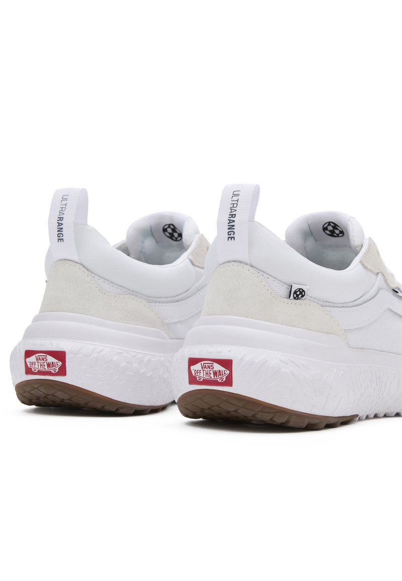 Zapatillas blancas con una mezcla de materiales suaves y texturizados, forma redondeada, suela gruesa y el logo "VANS OFF THE WALL" en el talón.