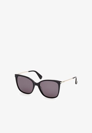 Lunettes de soleil noires œil de chat avec verres foncés et fines branches argentées avec embouts incurvés noirs sur fond blanc.