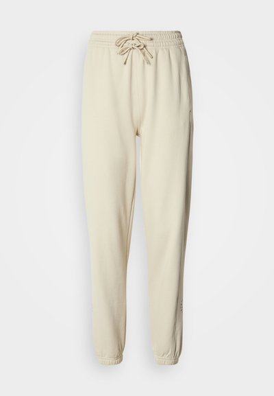 Μπεζ φόρμα από μαλακό ύφασμα, με ελαστική μέση και κορδόνι, μανσέτες στα τελειώματα και πλαϊνές τσέπες.