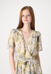  Rochie florală, în nuanțe de bej deschis, cu modele verzi și albastre, cu mânecile scurte tip fluture, decolteu adânc în V și talie ajustată cu un legătoare.