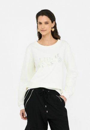 Felpa bianca con colletto rotondo, caratterizzata da un design decorativo luccicante. Abbinata a pantaloni jogger neri, che mostrano una vestibilità comoda e un cordoncino.