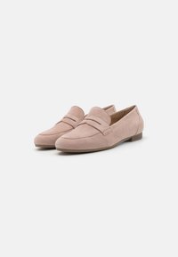 Mocassins en daim rose pâle avec un talon plat, un bout rond, et des coutures apparentes sur la tige. Design minimaliste avec une texture lisse.