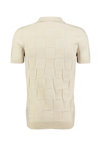 Polo shirt beige a maniche corte con un grande motivo a quadri in rilievo sulla schiena e polsini e orlo a coste.