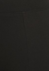 Svarta leggings av stretchtyg, med en slät yta och en figurnära design. Sömmar synliga längs sömmarna.