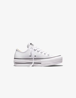Pantof sport Converse All Star alb cu talpă joasă, șireturi albe, dungi negre pe talpă și un capac texturat din cauciuc pe degetul piciorului, văzut din profil lateral.