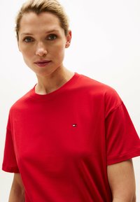 Rotes Baumwoll-T-Shirt mit Rundhalsausschnitt und kurzen Ärmeln. Verfügt über ein kleines Logo auf der linken Brustseite. Glatte Textur und lockere Passform.