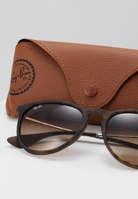 Ray-Ban sunglasses with a tortoiseshell frame and gradient lenses, accompanied by a brown leather case featuring a logo and textured finish.