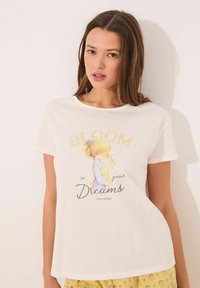 Witte katoenen T-shirt met een afbeelding van een meisje met een gele haarkleur, omringd door de tekst "BLOOM in your Dreams" in pastelkleuren.