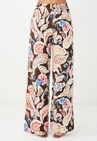 Braune weit geschnittene Hose mit einem floralen Muster in Pink, Blau und Creme. Das Material wirkt leicht und hat einen elastischen Bund.