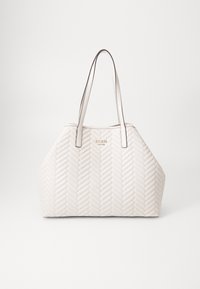 Sac fourre-tout beige matelassé avec un motif en chevrons, doté de deux longues anses et d'un accent de logo doré. Texture lisse et forme angulaire.