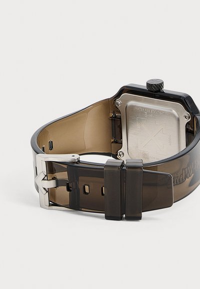 Bracelet de montre noir translucide avec boucle argentée et fond en acier inoxydable affichant la résistance à l'eau et les gravures du logo.