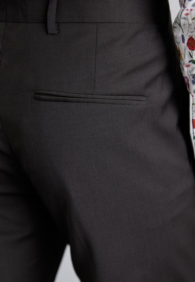 Dark grey tailored trousers made of smooth fabric feature a welt pocket at the back, with a clean finish and no visible fastenings.