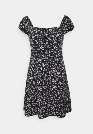 Schwarzes Kleid mit kleinen weißen Blumenmustern, Puffärmeln, einem quadratischen Ausschnitt und einer Knopfleiste. A-Linien-Form mit einem fließenden Rock.