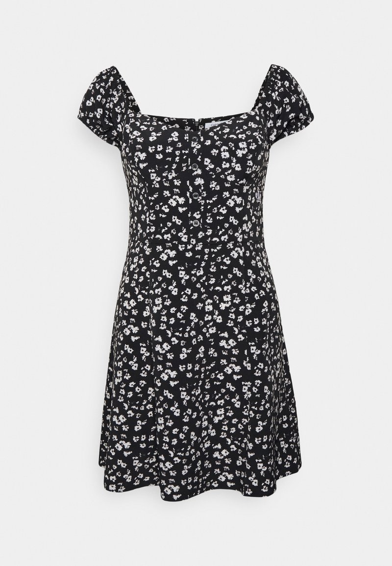 Svart klänning med små vita blommönster, puffärmar, fyrkantig halsringning och knäppning framtill. A-linjeformad med en flödande kjol.