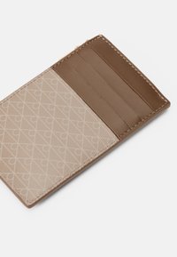 Portefeuille en cuir marron avec un motif texturé beige. Dispose de fentes pour cartes sur la gauche et d'un intérieur lisse marron. Détails de couture soignés.