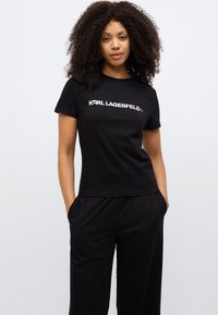 Tricou negru din bumbac cu logo alb „KARL LAGERFELD”. Mâneci scurte și design ajustat cu textură netedă.