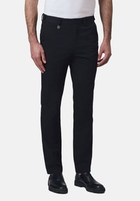 Czarne zwężane spodnie z bawełny, z płaskim przodem, paskami na pasek oraz eleganckim krojem, zestawione z czarnymi sznurowanymi butami.