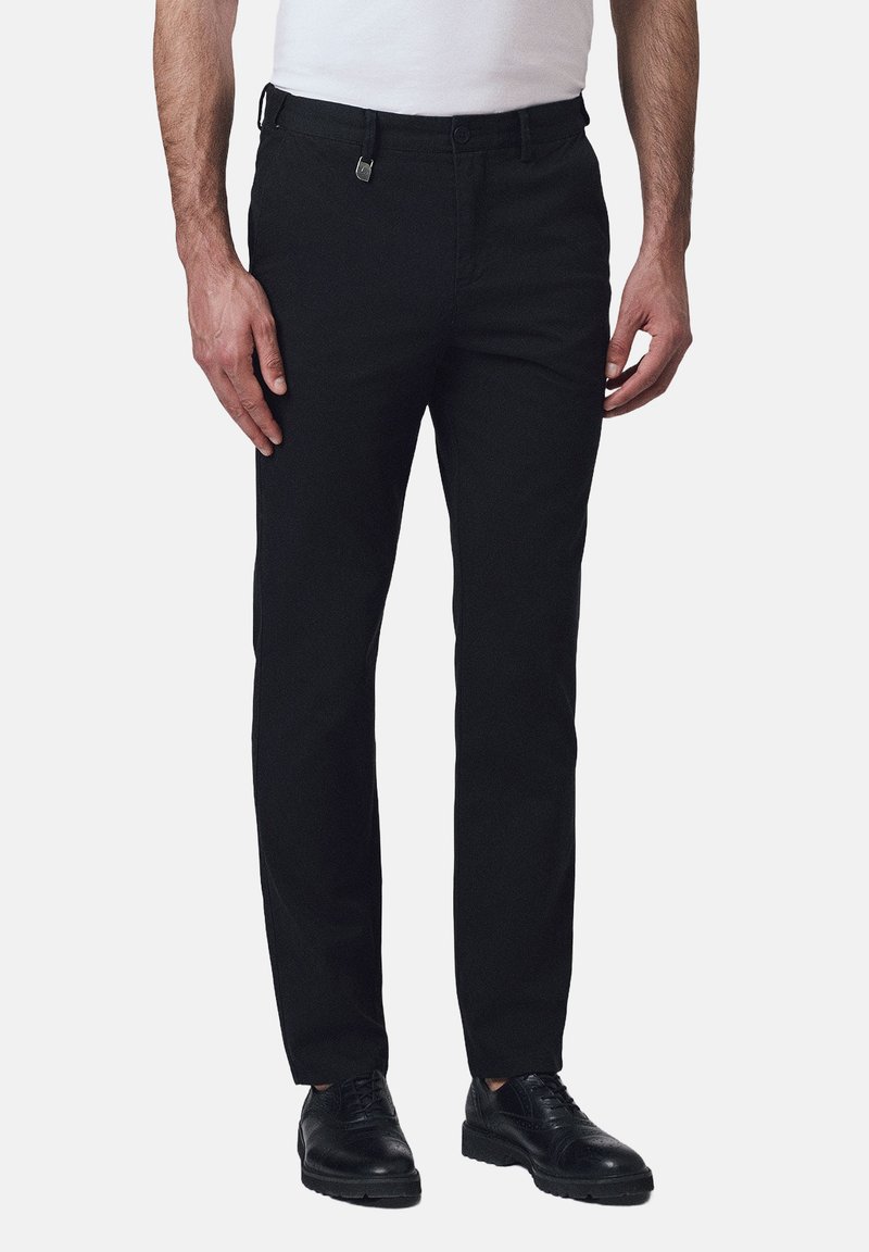 Czarne zwężane spodnie z bawełny, z płaskim przodem, paskami na pasek oraz eleganckim krojem, zestawione z czarnymi sznurowanymi butami.