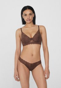 Conjunto de lencería de encaje marrón que incluye un bralette con bordes festoneados y un tanga a juego. La delicada textura de encaje realza el diseño general.