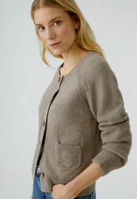 Hellbrauner gestrickter Cardigan mit gerippten Manschetten und Saum, ausgestattet mit einer einzigen Tasche und Holzknöpfen, texturiertem Stoff und rundem Ausschnitt.