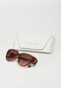 Óculos de sol Michael Kors em gradiente burgundy e castanho, com um detalhe de logótipo proeminente. Inclui uma caixa branca texturizada.