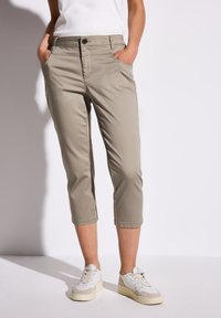 Beige capribyxor i lätt tyg, med framfickor, knapp- och dragkedjestängning, samt rak benform. Matchas med vita sneakers.