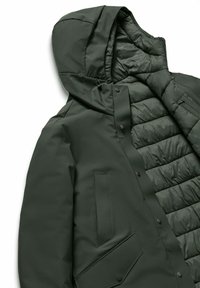 Giacca imbottita verde scuro con cappuccio, dotata di chiusure a scatto, fodera trapuntata e una grande tasca laterale. Tessuto liscio, design elegante.