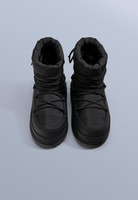 Černé zateplené boty s polstrovaným límcem, texturovanou podrážkou a tkaničkami přes hladký voděodolný povrch, navržené pro použití v chladném počasí.