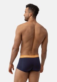 Boxers ajustados en color navy con una cinturilla naranja "ENDURAH". Tejido suave, diseño ceñido y corte de longitud media, mostrando una vista trasera limpia.