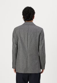 Blazer gri cu model houndstooth, cu un design structurat, rever tip notch, fanta simplă și manșete cu trei butoane. Materialul are un aspect texturat.