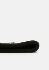 Tela de punto negra doblada, mostrando una textura suave y un borde redondeado. Diseño simple sin patrones o acentos adicionales.