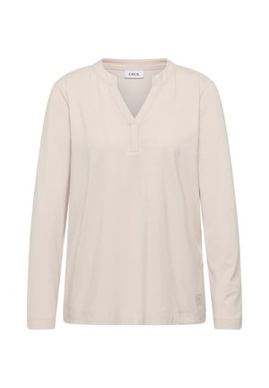 Licht beige lange mouw top met V-hals, gemaakt van zacht materiaal. Heeft een subtiel logo aan de onderkant van de linkerzijde.