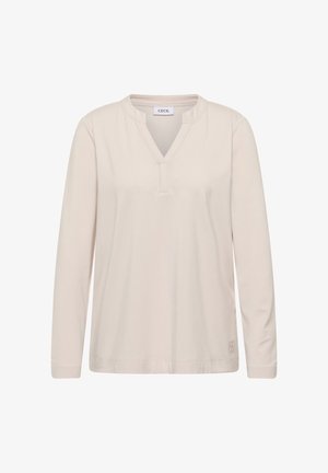 Licht beige lange mouw top met V-hals, gemaakt van zacht materiaal. Heeft een subtiel logo aan de onderkant van de linkerzijde.