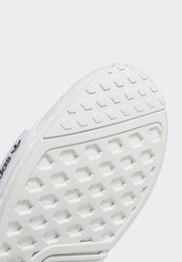 Suela de zapatilla blanca con un patrón hexagonal, que presenta una superficie texturizada para un mejor agarre. El logo lateral aparece en negro. Diseño limpio y minimalista.