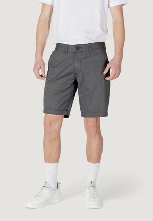 Pantaloni corti grigi a fantasia con vestibilità rilassata, chiusura con bottone e tasche laterali, abbinati a sneakers bianche e calze.