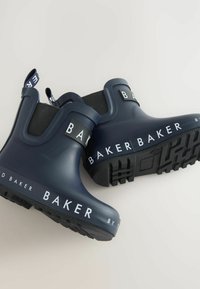 Bottines en caoutchouc bleu marine avec des panneaux latéraux élastiques noirs, une marque blanche à l'avant et des semelles noires texturées pour une meilleure adhérence.