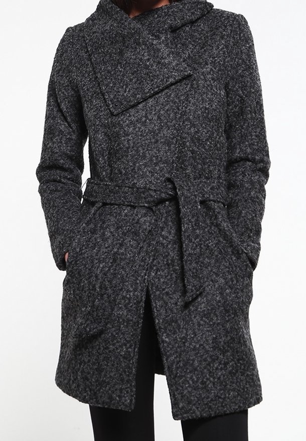 Manteau en laine texturée gris foncé avec grand col, taille ceinturée, mains dans les poches latérales, porté sur un pantalon noir.