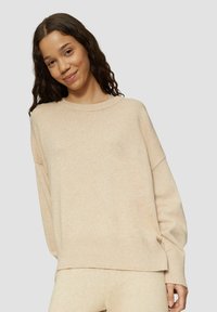 Beige neulepaita, jossa on leveä ribbireuna ja laskostetut olkapäät. Teksturoidusta kankaasta valmistettu, rento malli, jossa on ribbireunus.