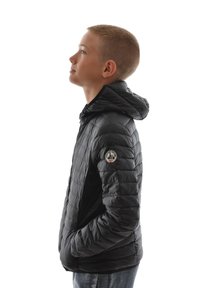 Doudoune noire avec capuche, disposant d'un design matelassé, de poches latérales et d'un patch logo circulaire sur la manche gauche.