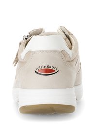 Beige Sneaker mit einer strukturierten Oberseite und einer weißen Fersenkappe. Verfügt über ein auffälliges Logo in Rot und Schwarz auf der Ferse sowie eine gepolsterte weiße Sohle.