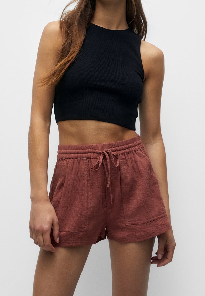 Zwarte geribde crop top gecombineerd met roestkleurige, gestructureerde shorts met een elastische tailleband en trekkoord, zijzakken en een losse pasvorm.
