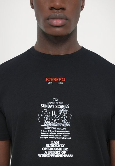 Black cotton t-shirt featuring white graphic text and cartoon figures. Red "ICEBERG 19*74" printed above the design. Round neckline.