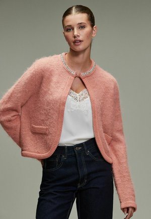 Helles rosa, verkürztes Cardigan aus flauschigem Material, mit einer gestrickten Kante, rundem Ausschnitt und einer einzelnen Vordertasche mit dezentem Glanz.