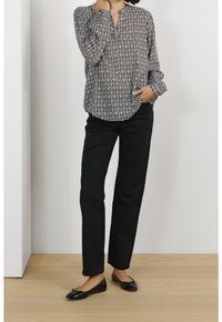 Svartvittryckt blus med bladmönster, krage, långa ärmar, ihop med svarta raka byxor och svarta ballerina.