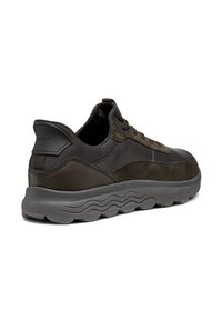 Zapatilla marrón oscuro hecha de cuero y gamuza, con una suela de goma ondulada, diseño de cordones y un cuello acolchado para mayor comodidad.