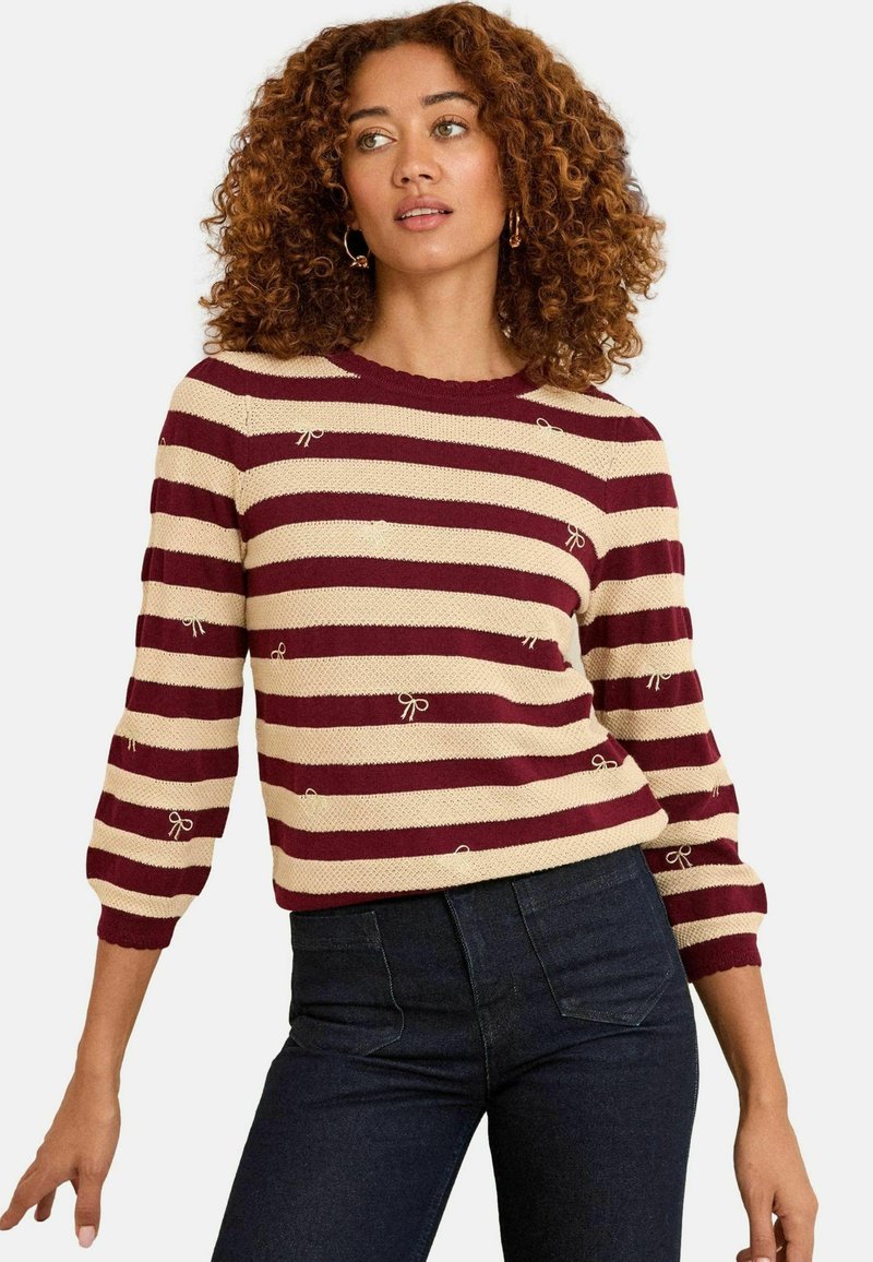 Pulover striped în culori bordo și crem, cu guler rotund, mâneci până la cot și detalii cu fundițe în întreaga design.